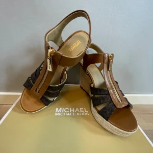 Michael kors kilklacksskor  - Högklackade skor från Michael Kors i stl. 38,5 som är helt nya, aldrig använda. Säljs i original förpackning. Inköpta på Boozt för 1500:-. Mitt pris 1150:-.