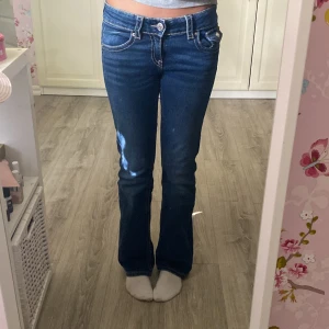 Mörkblå lågmidjade bootcut jeans - Säljer ett par snygga mörkblå bootcut jeans från Gina tricot Young i storlek 152. De är lågmidjade och har fickor med knappar och lock. Jeansen är i bra skick och har inga defekter!! 🩷