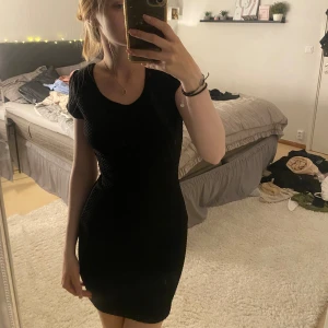 Svart kortklänning med öppen rygg - Säljer en snygg svart kortklänning med öppen rygg och korsade band. Klänningen är tight och perfekt för fest. Den är ärmlös och har en enkel men elegant design. Perfekt för en utekväll eller en speciell tillställning. Köp direkt eller ge prisförslag 💛