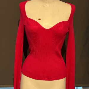 Röd ribbad topp från H&M - Säljer en snygg röd ribbad topp från H&M. Den har en tight passform och långa ärmar. Toppen är offshoulder och perfekt för både vardag och fest. Materialet är mjukt och stretchigt, vilket gör den bekväm att bära. Aldrig använd.