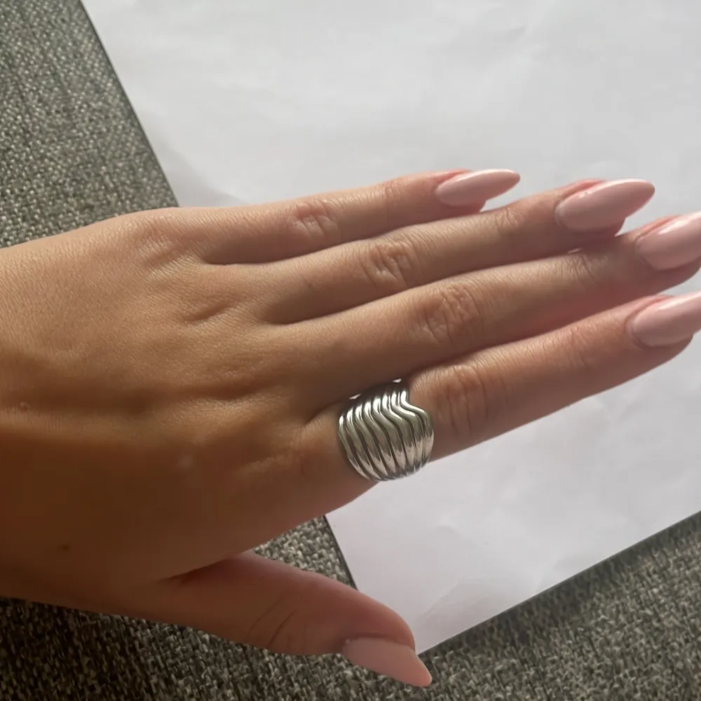 Säljer en snygg och unik silver ring med ett vågigt mönster från Edblad . Ringen är i ett modernt och stilrent design som passar perfekt till både vardag och fest. Den ger en cool touch till din outfit. säljer den för den inte kommer till användning💕. Accessoarer.