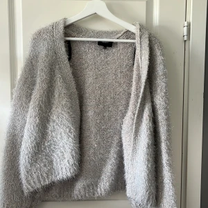 Mysig grå kofta - Säljer en supermysig grå kofta som är perfekt för kyliga dagar. Den är stickad och har en fluffig textur som gör den extra varm och skön. Koftan har en öppen design utan knappar eller dragkedja, vilket gör den lätt att slänga på sig över en t-shirt eller topp. Perfekt för höst och vinter! 💖