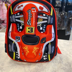 Röd och svart ryggsäck med bilmotiv - Säljer en cool ryggsäck med ett häftigt bilmotiv i rött, svart och gult. Väskan har justerbara röda axelremmar och en dragkedja med ett hjulformat dragkedjehandtag. Perfekt för skolan eller utflykter!