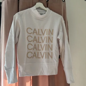 Calvin Klein Sweatshirt - Vit sweatshirt fårn CK, knappt använda, guldiga stenar & lite högre i nacken. Köpt i butik.
