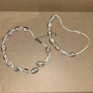 Vita snäckskalssmycken - Säljer två superfina halsband med vita snäckskal. Det ena halsbandet har en justerbar kedja och det andra har en knytbar tråd. Perfekta för sommarens alla äventyr och strandhäng! 🐚✨