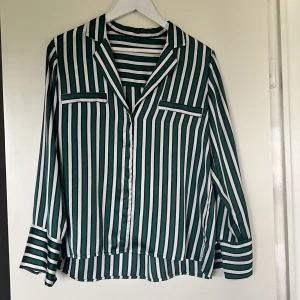 Grön- och vitrandig blus - Grön- och vitrandig siden skjorta från Ginatricot. I mycket gott skick, inga skavanker. Använda några gånger.