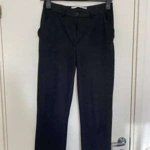 Svarta kostymbyxor - Säljer ett par svarta kostymbyxor i storlek dam Xs. Byxorna är lågmidjade. De är väldigt bekväma samtidigt som de är väldigt snygga. Byxorna har en dragkedja och knapp framtill samt fickor på sidorna. De är i mycket bra skick!
