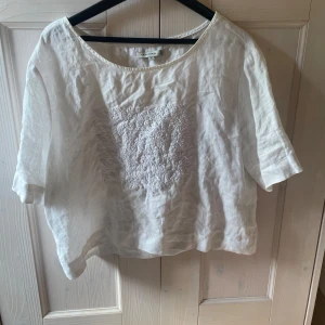 Vit blus från Flash Woman - Säljer en vit blus från Flash Woman i storlek XL. men tycker den passar mig som har S/SX. Blusen har en lös passform och är tillverkad i ett lätt och luftigt material, perfekt för varma dagar. Den har korta ärmar och ett vackert broderat mönster på framsidan. Perfekt för en somrig och avslappnad look! 💗