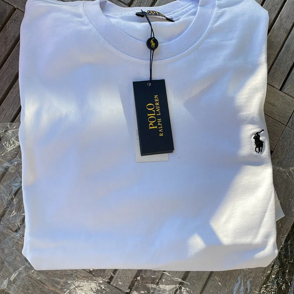 Säljer en snygg vit t-shirt från Polo Ralph Lauren. Den är i storlek L och har en klassisk design med en liten broderad logga på bröstet. Perfekt för en stilren och avslappnad look. T-shirten är gjord av mjuk bomull och är superbekväm att ha på sig. Passar perfekt till både vardag och fest! omvänd helt ny!!. T-shirts.