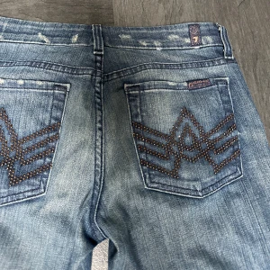 Blå jeans från 7 For All Mankind - Säljer ett par lågmidjade bootcut jeans från 7 For All Mankind i superfin tvätt. De har fina detaljer på bakfickorna. Jeansen är i bra skick och uppsprätta där nere. Säljer då de är något korta på mig (167). 