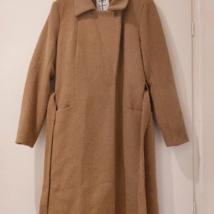 Ny kappa från Only  - Kappa med bälte Knapp och tryckknapp framtill 2 fickor fram Avtagbart bälte Faller vid knäna