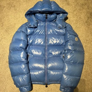 Moncler Maya - Säljer den sjukt fina Moncler maya i sky blue, tyvärr så har cartoon lossnat samt finns ett jätte litet pinhole vid armen men utöver de så är den fint skick! Den är i färgen sky Blue, vilket är en väldigt speciell färg, svår att få tag på!