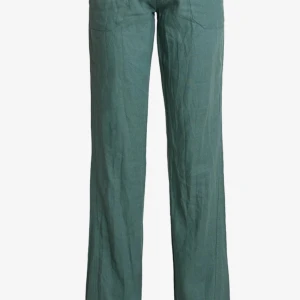 Gröna linnebyxor med snörning - Ett par gröna linnebyxor med snörning i midjan. Byxorna har en lös passform och raka ben, vilket ger en bekväm och avslappnad stil. Perfekta för sommarens varma dagar.