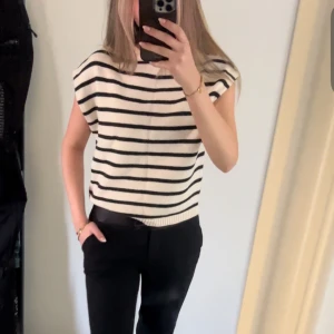 Randig ärmlös topp - Ärmlös stickad topp med svartvita ränder från Gina. Toppen har en lös passform och är väldigt skön!