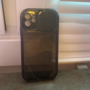 Svart mobilskal med kameraskydd - Ett svart mobilskal med inbyggt skydd för kameran. Skalet är genomskinligt och har en liten spegel samt så att det skyddar karman. jätte bra skick och det är för  IPhone 11