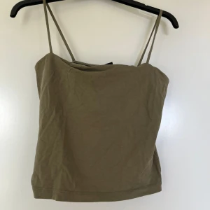 Olivgrön linnetopp - En enkel och stilren olivgrön linnetopp med tunna axelband. Toppen är kort och har en rak passform. Använd enbart några gånger.