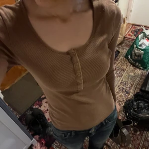 Långärmad topp från Gina - Jättefin långärmad topp med knappar från Gina. Ribbat tyg. Jätteskön och bekväm.