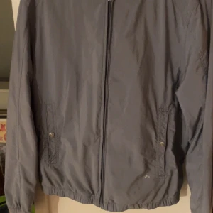 J Lindeberg jacka - Ljusblå j lindeberg jacka med luva som går att ta in eller ha ute. Tyvärr liten fläck på framsidan men inget man tänker på 