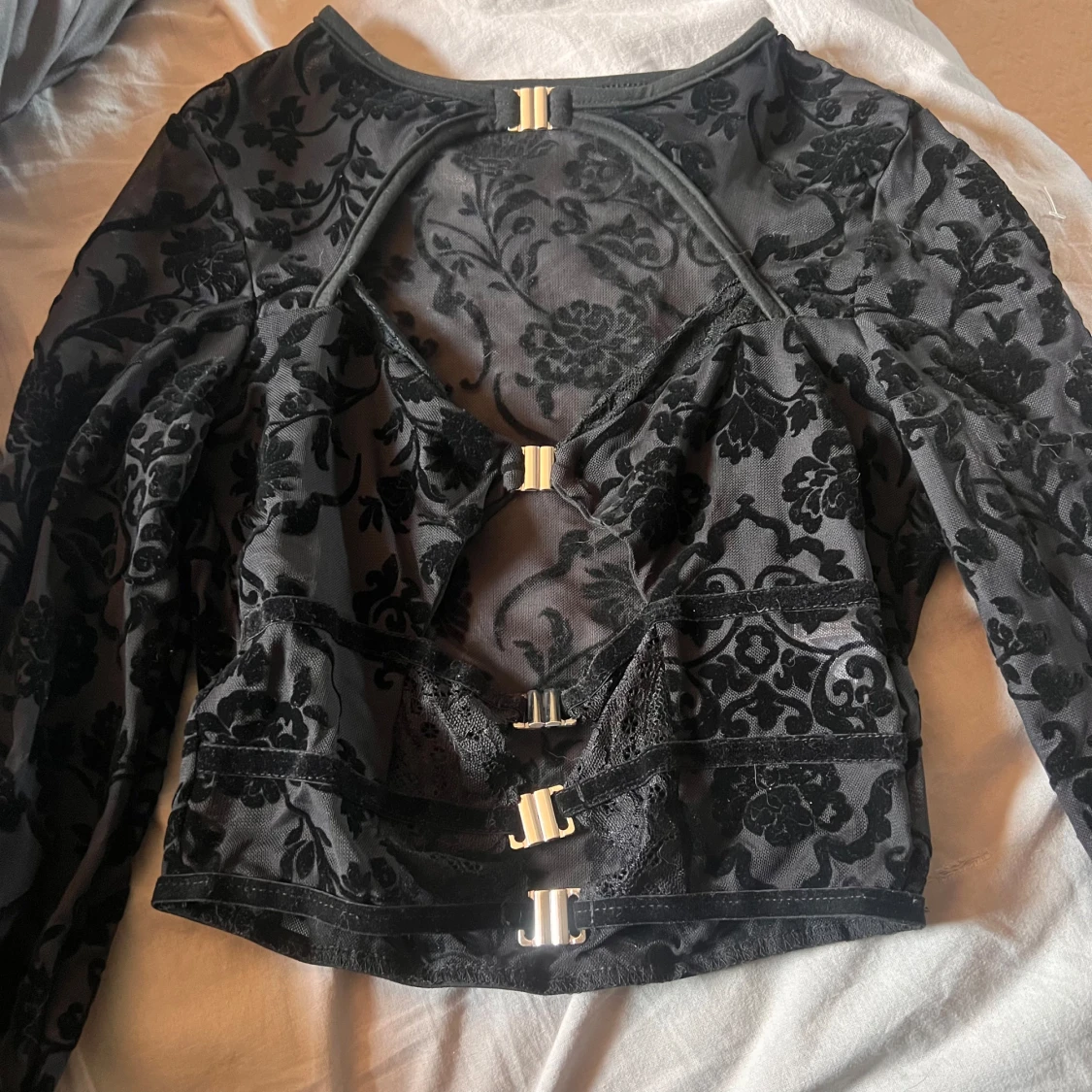 Svart blus med spetsdetaljer och spännen