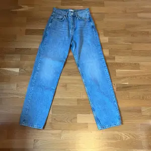 Ett par ljusblå högmidjade jeans i en lössittande modell från Gina tricot. Jeans är oanvända. 