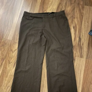 Bruna kostymbyxor  - Brun randiga lågmidjade kostymbyxor med vida ben