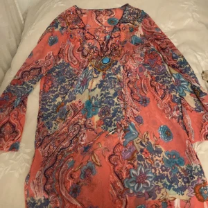 Klänning med blommor! - Blommig klänning med massor av färger! Den är i väldigt skönt och tunt material. Den är genomskinlig, men fint att ha över bikini eller en annan klänning ❤️Varirfrån den kommer och storlek vet jag inte, men passar s/m! Den har små stenar och pärlor! ❤️
