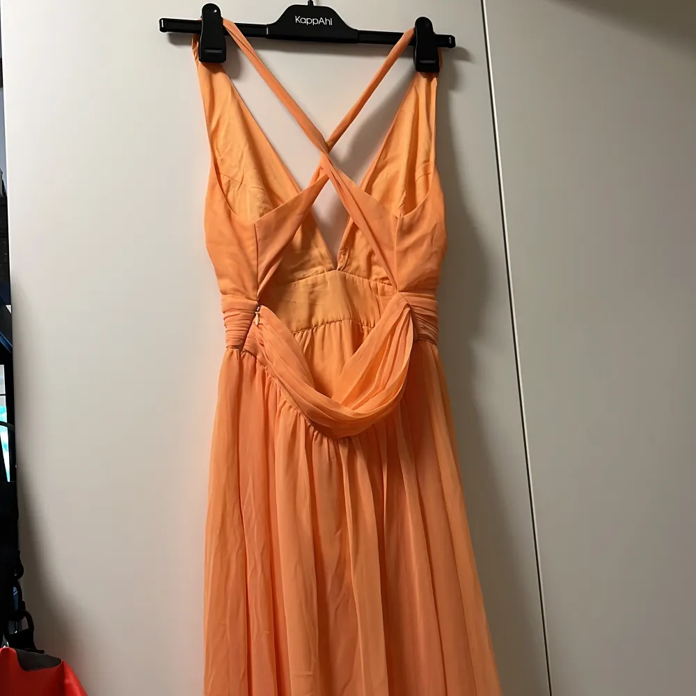 Balklänning från Nelly i färgen peach med korsad rygg. Använd 1 gång på bal. Vadderade bröst.  Klänningen är mer orangefärgad på bilden.. lite mildare åt rosa hållet i verkligheten. . Klänningar.