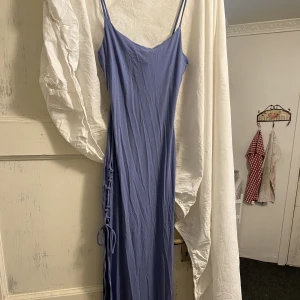 Långklänning med slits - Figurnära lavendel långklänning med snörad slits.  Aldrig använd
