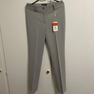 Byxa  - En helt ny och jätte stilig byxa som inte ens är använd en gång, som man också kan se av etiketten. Den har en fin grå färg och är jätte snygg. Har också med sig en svart bälte som också är oanvänd 