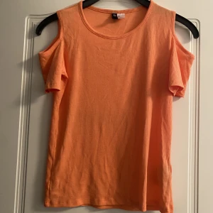 Orange T-shirt från H&M  - Fin t-shirts där axlarna syns. Cold shoulder T-shirt. Ser ut som ny och har en fin orange färg. Från H&M divided.