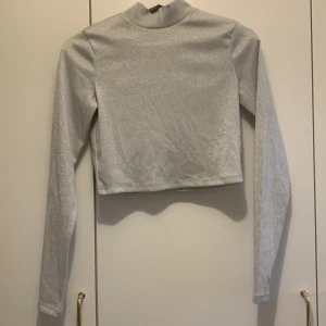 Glittertröja - Vit/grå glittrig polotröja från h&m i en lite kortare modell. Storlek s och endast använd en gång. Säljer för 60kr+frakt🤍