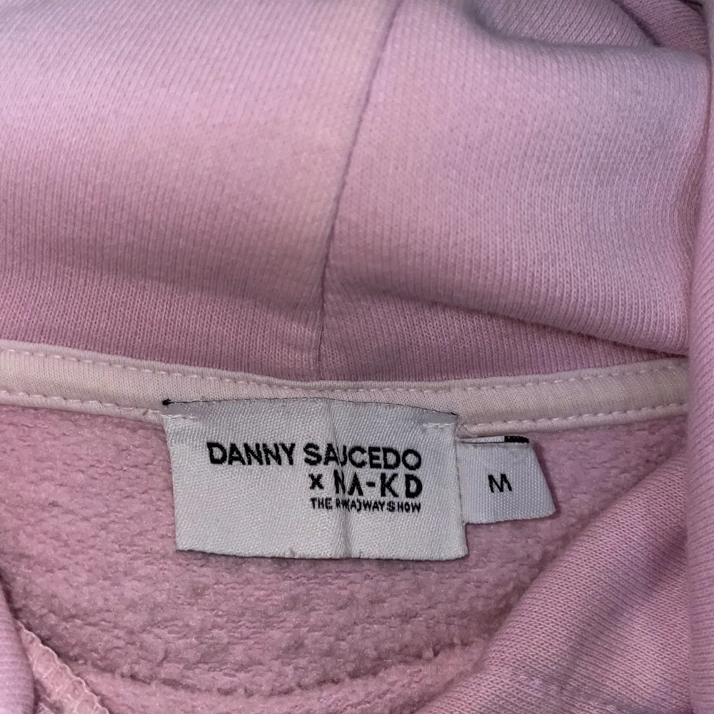 Danny saucedo X NAKD Collektion från 2019. Ljusrosa oversized hoddie med tjocka band. Stor och mysig huva med logga baktill.  Fint skick.  Passar s-L beroende på hur man vill att den ska sitta.. Hoodies.