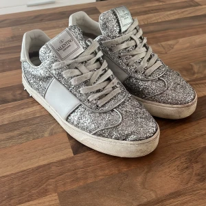 Valentino skor - Säljer dess glittriga valentino då jag ska flytta till USA och ej vill ha me dem dit. Jag har råkat slänga lådan med kvitto i av misstag men skorna är köpa på vestiare collective och jag kan skicka privat bild på själva köpet därifrån. Alla nitar kvar!! 