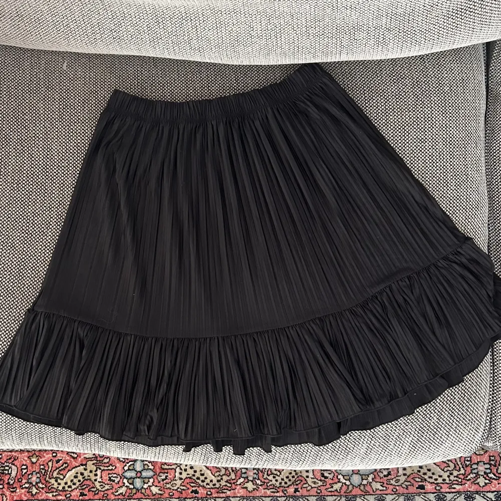 Zara svart plisserad kjol med volang längst ner. Väldigt bra skick, knappt använd. Stretchig så passar flera storlekar. . Kjolar.