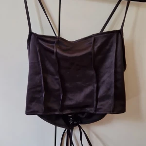 Topp med knytdetalj - "Ribbad"? Framsida? Korsett-knytliknande rygg. Passar även L.