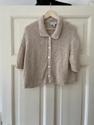Kofta - Other Stories - Beiga, kortärmad stickad kofta från Other Stories. Använd ett fåtag gånger i bra skick. Koftan ska nog se lite ”använd ut” då den såg ut som det när den var ny. 