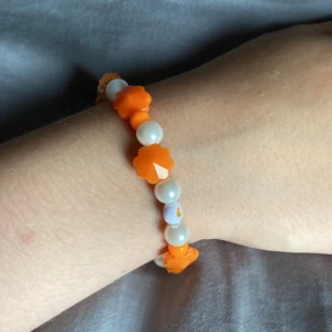 Armband - Ett orange armband med några vita pärlor på🧡🤍