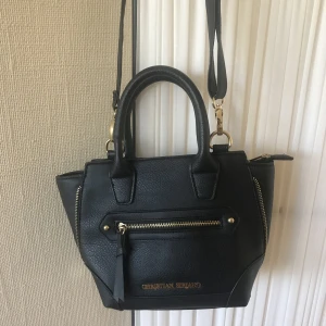 Christian Siriano väska - Svart väska från Christian Siriano inköpt i Dubai. 29 cm på det bredaste stället och 31 cm hög med handtag. Hämtas i Huddinge eller på Södermalm. 