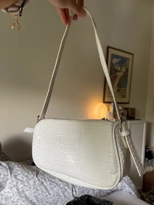 Vit axelväska - Vit axelväska perfekt till vardags och fest! Inuti har den ett stort fack och ett mindre fack. Rymlig. Köpt från Nelly och är i mycket bra skick!🤍🤍🤍