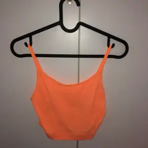 Ett orange linne i neon färg. Använt bara få gånger och är i använt nytt skick. Sitter tight o funkar utan bh också.