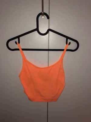 Orange linne - Ett orange linne i neon färg. Använt bara få gånger och är i använt nytt skick. Sitter tight o funkar utan bh också.