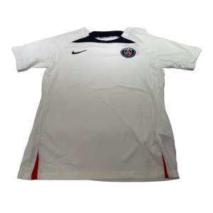 En PSG-tröja i storlek M som är vit. Den är perfekt passande och av hög kvalitet. Dess andningsförmåga gör den idealisk för både matcher och träning.