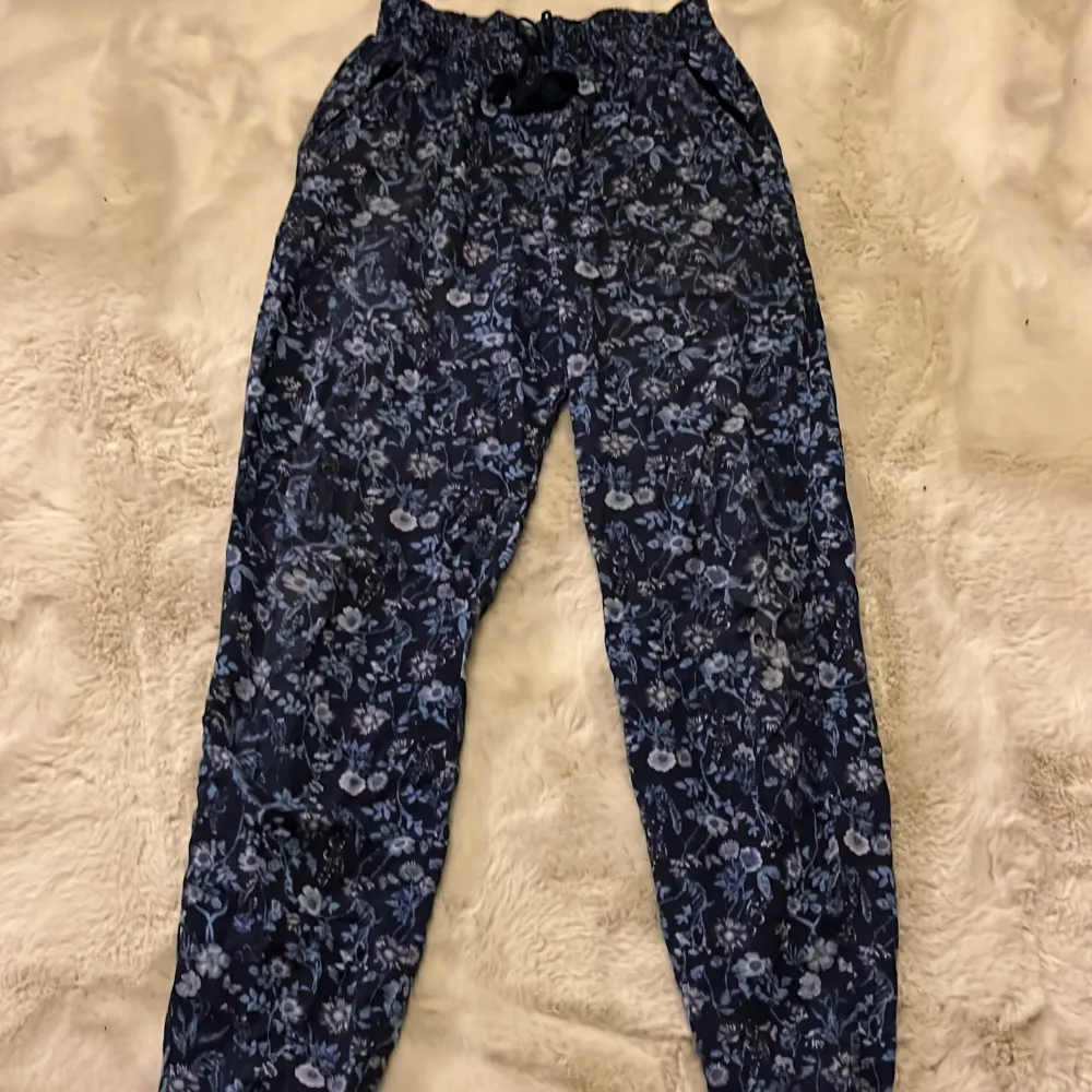 Blåa sköna luftbyxor. Storlek 158😊Byxorna är i väldigt bra skick! De har små blåa blommor och växter som detaljer. . Jeans & Byxor.