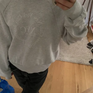 Grå hoodie NYC - Grå hoodie med sydd tryck med NYC och som är varm och som har inga skador