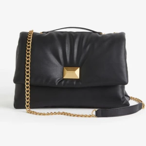 Svart vadderad väska från hm 😍 - Anvönd 1 gång bara! Den är lite större än en vanlig axelremsväska stilren och väldigt rymlig 😍✨ påminner om märket Valentino ✨😍 med den stora guld niten framtill. Den svarta är slut på hemsidan den kostar 399kr annars men finns ej kvar att köpa 