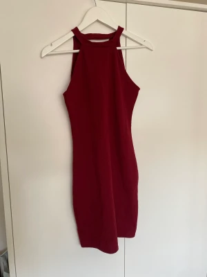 Klänning - Fin festklänning från New look i vinrött. Är en typ av mönster i jaquardstil på tyget. Halterneck med key hole på ryggen. I fint skick och nytvättad. 