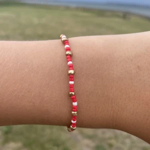 Pärlarmband  - Ett rött, vitt, guldigt pärlarmband i storlek s men finns också i fler storlekar om man vill ha, kontakta oss om de finns frågor!💕