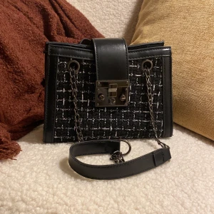 Handväska - Jättegullig handväska i svart och vit med en kedja, ganska liten men väldigt rymlig ändå. Köpt på sellpy men har inte kommit till användning så säljer vidare den här på plick istället!