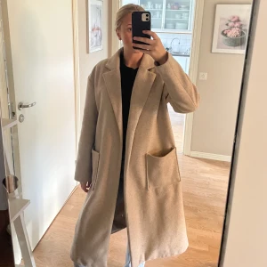 Lång beige kappa - En lång beige kappa från Gina. Bandet runt är borta, men är jättefin utan också. Säljer då den inte används längre 🩷