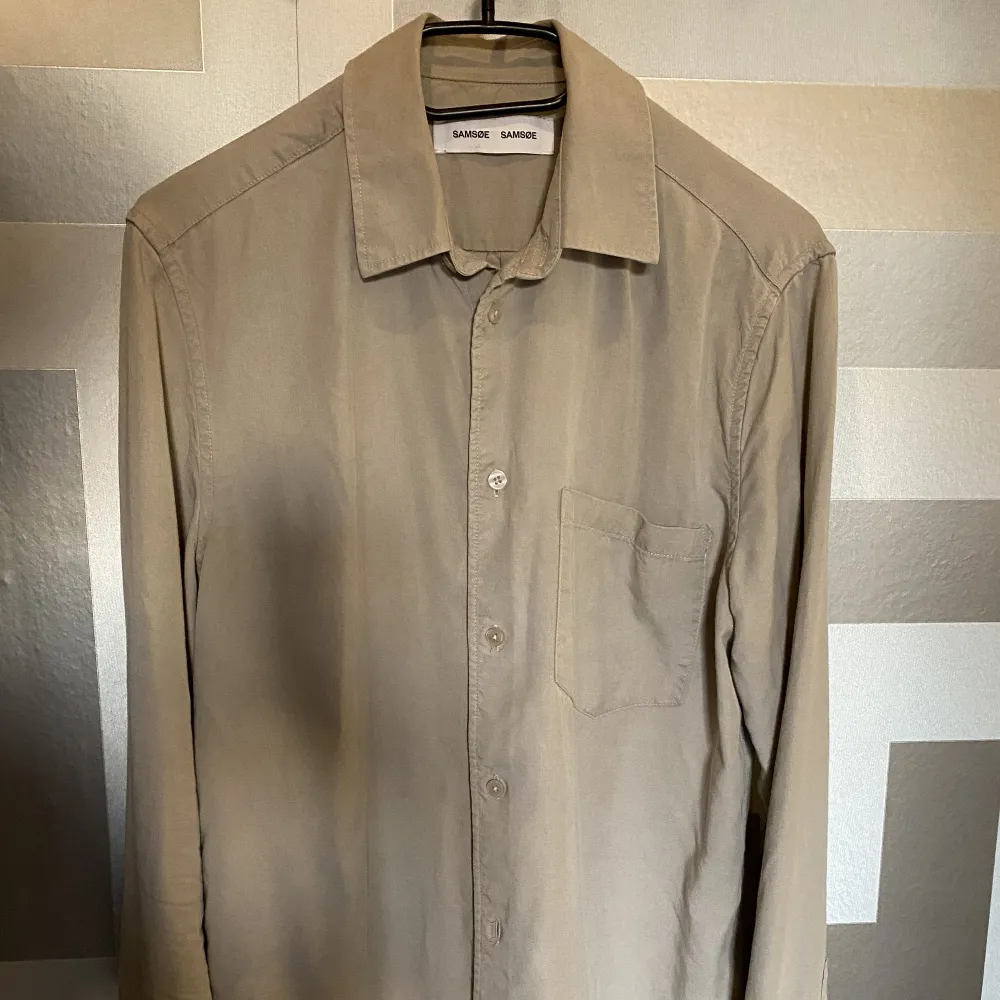 Snygg beige Samsøe skjorta, använd skick 9/10.   Material 100% lyocell, vilket är ett extremt mjukt material och skapar fint fall på skjortan.  Säljs pga garderobsrensning då denna inte längre används  Köpt för 1100kr. Skjortor.